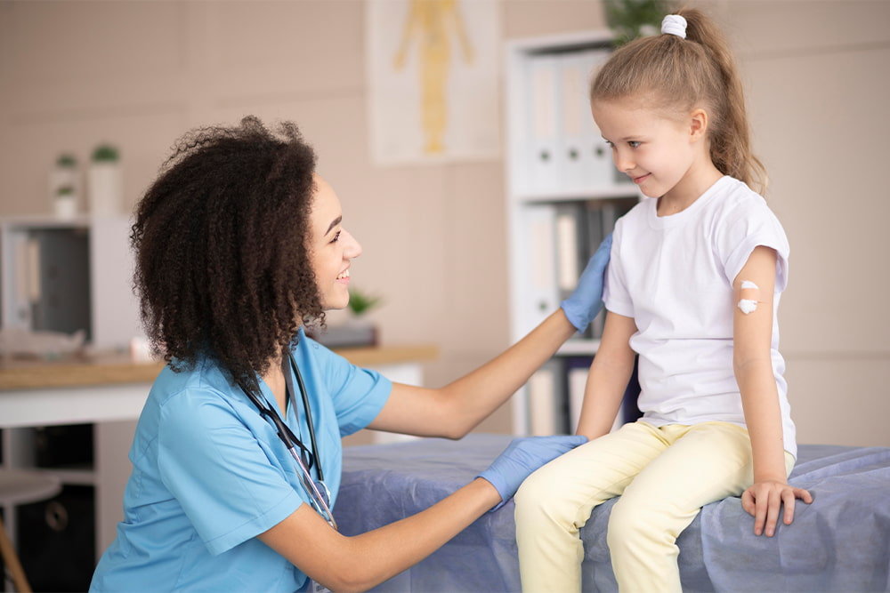 Niña en consulta de pediatría siendo vacunada.